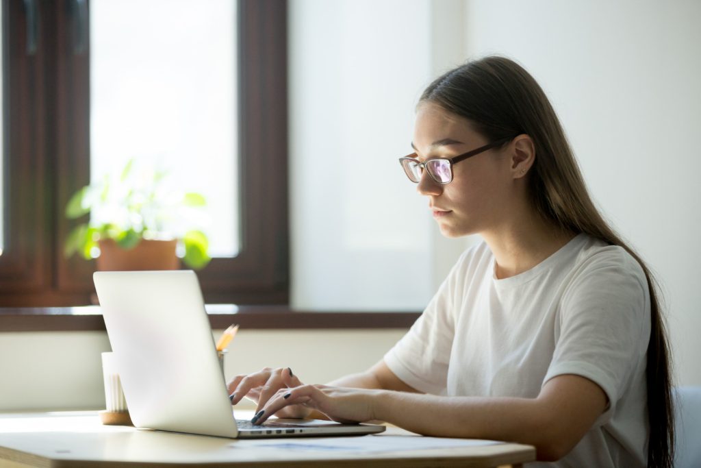 Jeune femme à lunette écrivant sur l'ordinateur